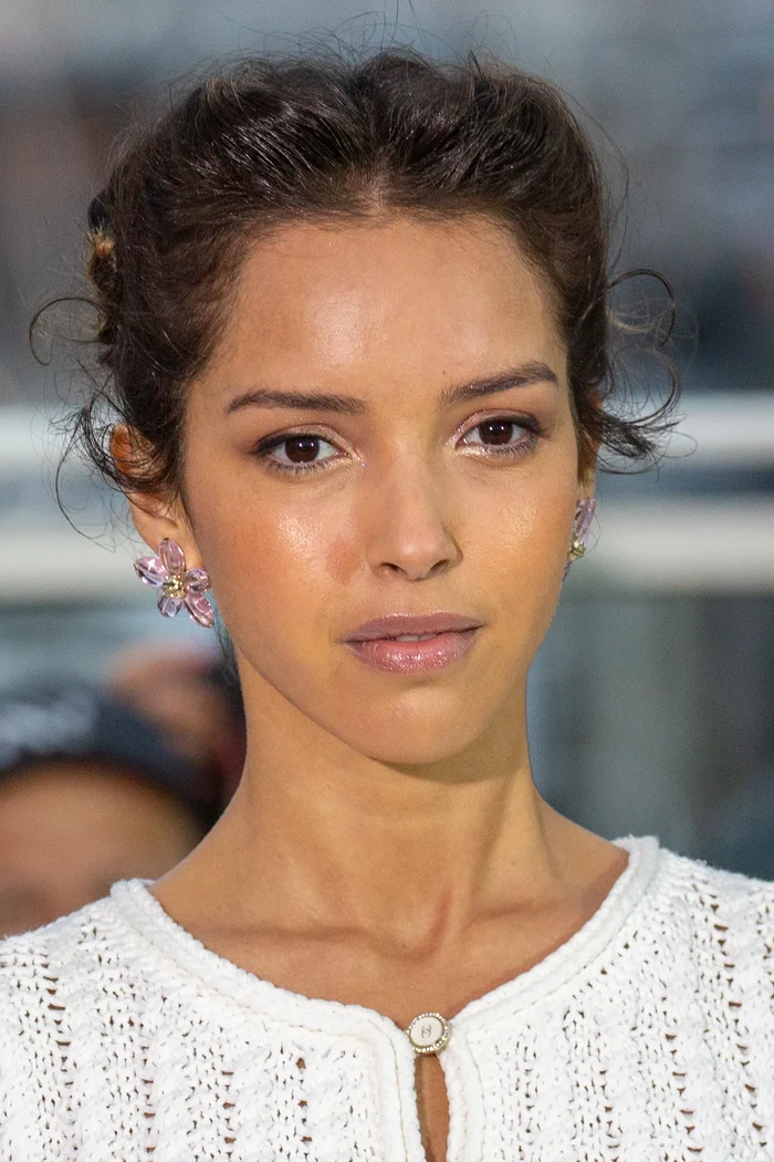 Lyna Khoudri en haut blanc brodé, cheveux relevés et boucles d'oreilles sur photocall de Cannes