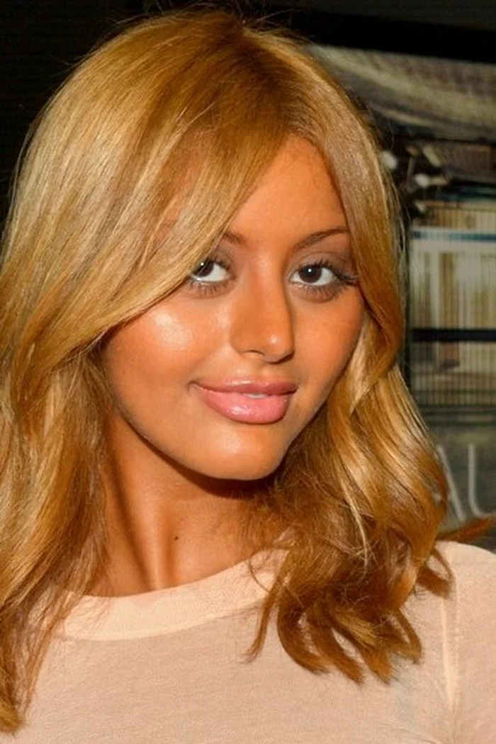 Zahia Dehar aux cheveux blonds ondulés, maquillage lumineux et haut clair