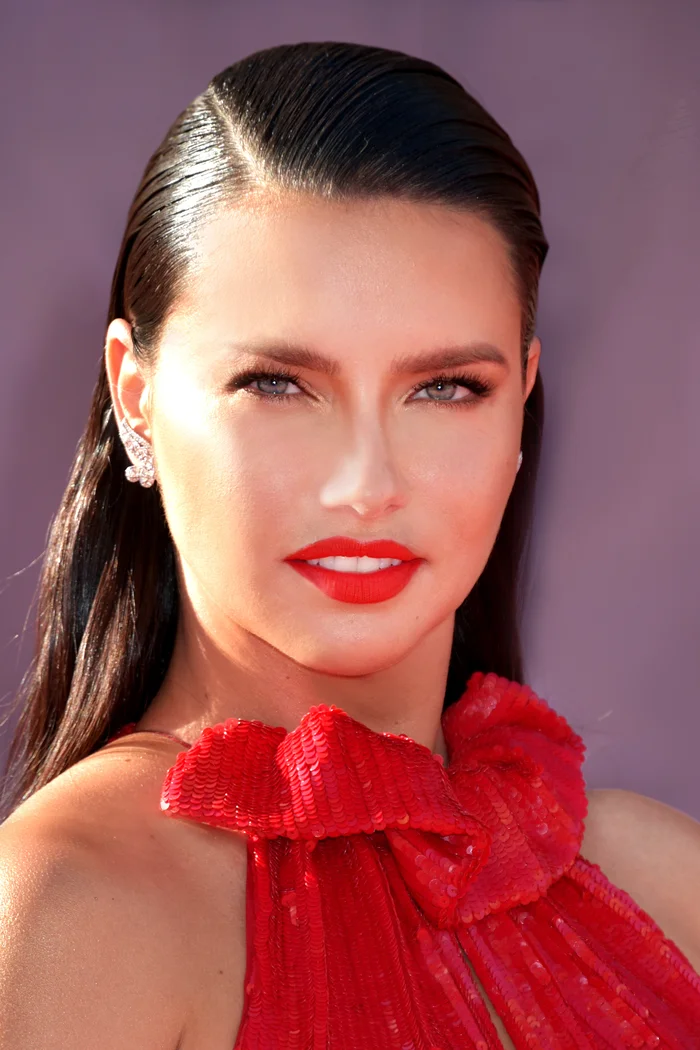 Adriana Lima en portrait de gala, cheveux bruns lissés et robe rouge à sequins