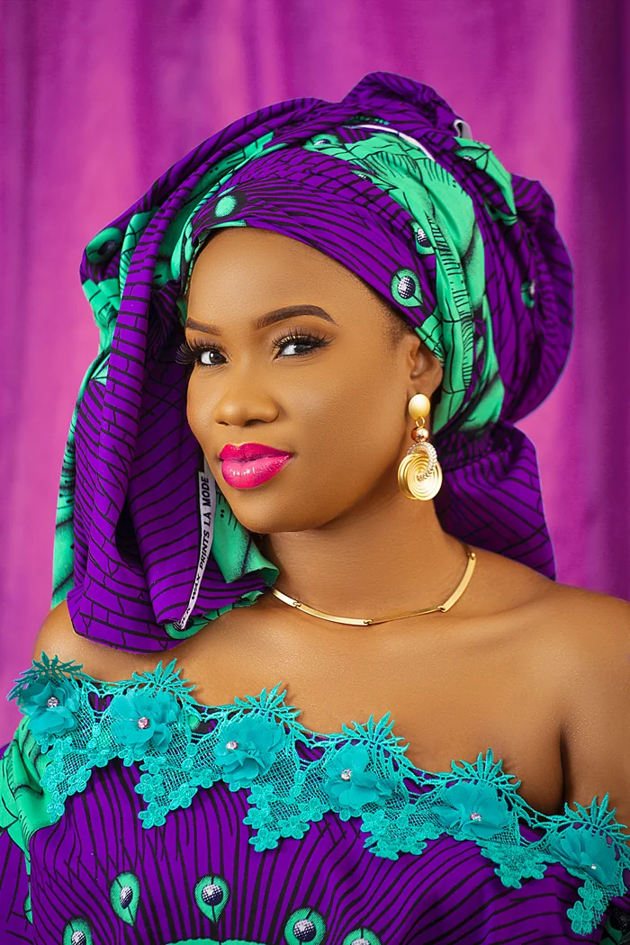 Faty en portrait studio avec foulard violet et vert, robe turquoise et bijoux dores