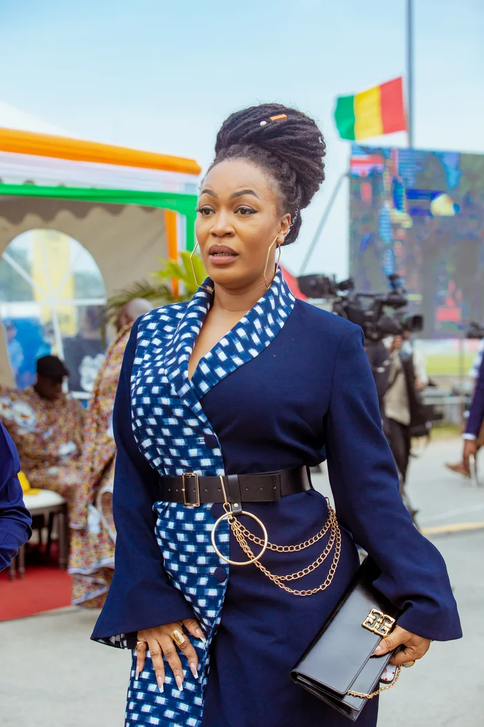 Josey en tenue bleue a motif blanc avec chignon tresse et accessoires dores lors d'un evenement