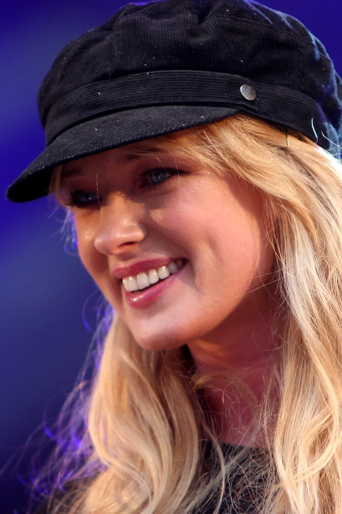 Eda-Ines Etti, chanteuse estonienne née à Haapsalu, sourire lumineux sous casquette noire et cheveux blonds