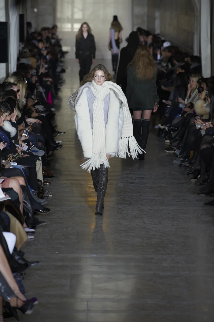Enikő Mihalik au défilé Jill Stuart, silhouette en manteau clair et bottes noires sur podium