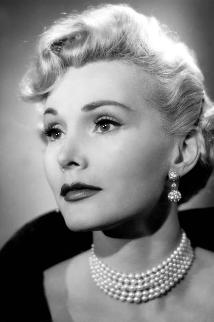 Zsa Zsa Gabor en portrait studio noir et blanc, coiffure blonde hollywoodienne et collier de perles