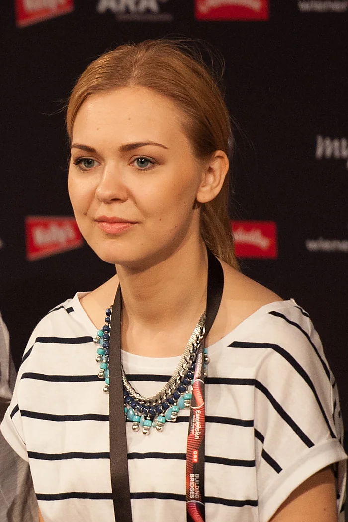 Monika Linkytė, chanteuse lituanienne, portrait presse avec cheveux roux attachés et haut rayé