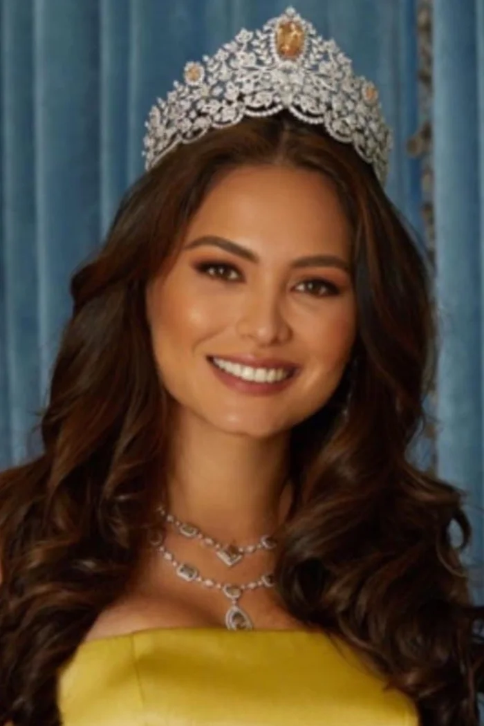 Andrea Meza souriante avec sa couronne de Miss Univers et une robe jaune