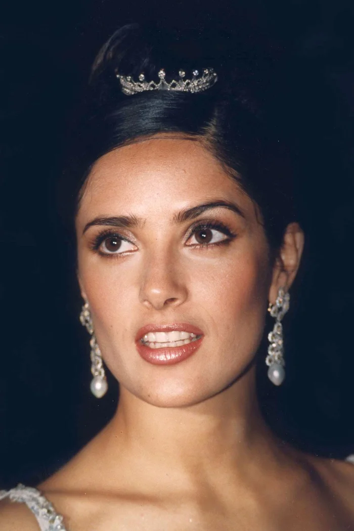 Salma Hayek en portrait de gala avec chignon haut, diadème et boucles d'oreilles