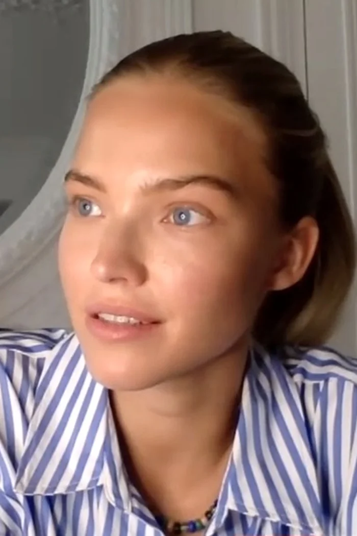 Sasha Luss, mannequin et actrice russe aux cheveux tirés en arrière, chemise rayée bleue et blanche