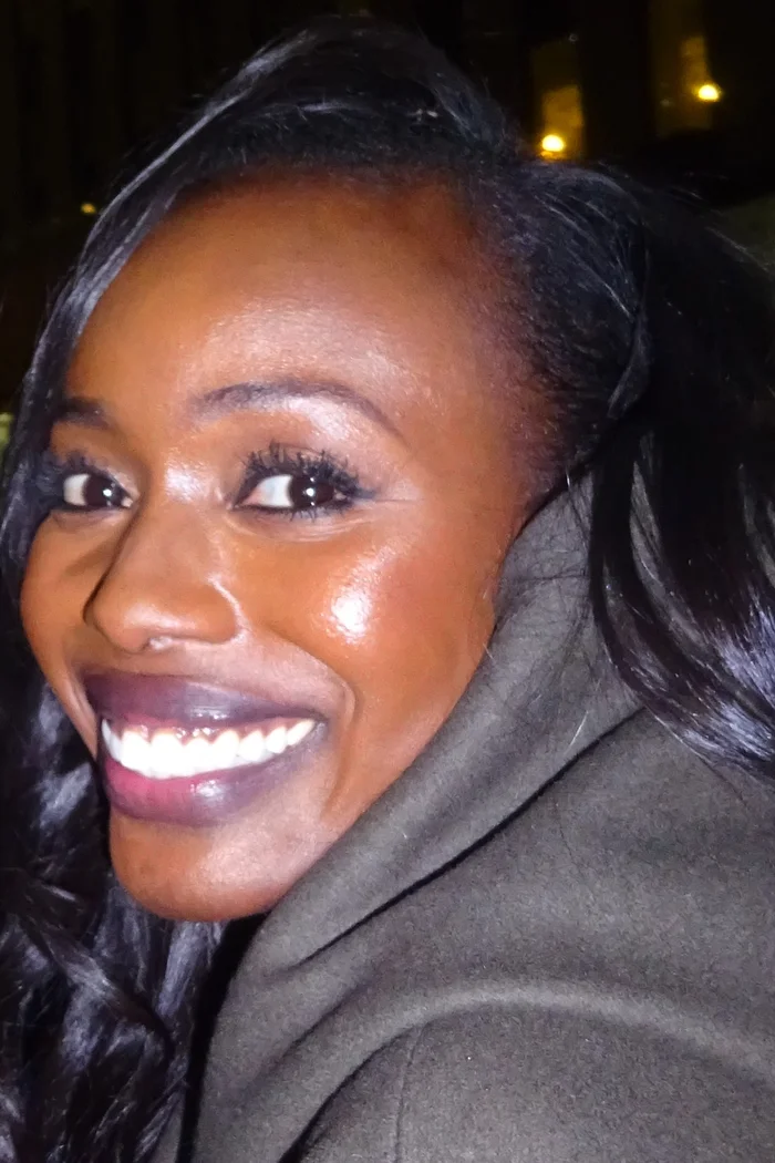 Anna Diop souriante en portrait rapproché avec cheveux noirs et lumière de soirée